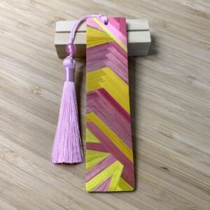 Marque pages artisanal en marqueterie de paille aux motifs géométriques rose et jaune avec pompon rose et perle.
